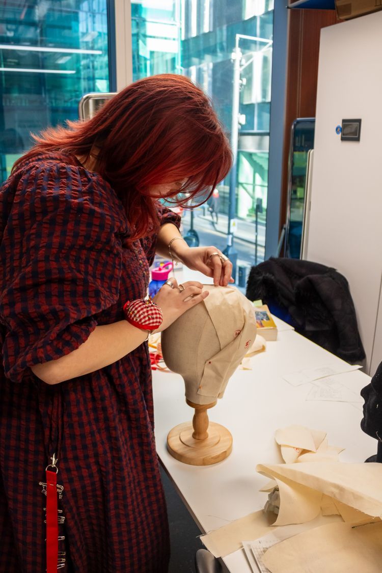 Beca Roberts working on a tudor style headdress on a mannequin's head